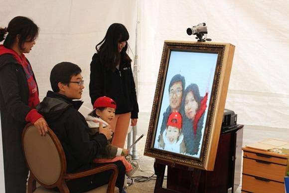 "우리 가족 예쁘게 나오게 해주세요" ETRI에서 자체 개발한 디지털 초상화 기술로 가족사진을 찍고 있는 한 가족. 