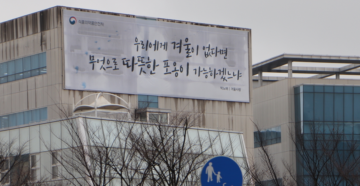 질병관리본부 앞 식품의약안전처 건물에 박노해 시인의 겨울 사랑 문구가 적혀 있다. <사진=김인한 기자>